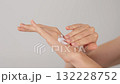 Close-up of female hands applying moisturizing cream on neutral background. Hygiene, Body care, and Skincare concept.  132228752