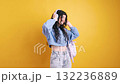 Young student listening to music and dancing on yellow background 132236889