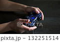 A close-up shot captures hands skillfully navigating a blue video game controller. The illuminated buttons add to the immersive gaming experience. Perfect for themes of leisure and modern 132251514