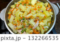 Cooking a vegetable stew with chicken in a cauldron at home. Onions, carrots, bell peppers, chicken breast, green peas, potatoes, and spices are the ingredients for a delicious and flavorful dinner. 132266535