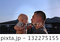 Happy young father holds and kisses adorable baby boy in cottage backyard 132275155