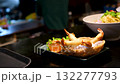 Close-up of grilled whole shrimp covered in green herb sauce, garnished with fresh cilantro leaves. 132277793