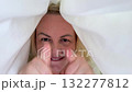 Adult woman in robe under blanket making funny faces, smiling, pointing fingers at camera, playful morning mood and positive emotions at home 132277812