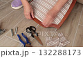 Anonymous person restore old vintage chair in home. Fabric replacement. Antique furniture and modern striped linen and cotton fabric. Hobbies, crafts, and retro-minimalist style. 132288173