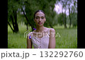 Beautiful young woman in pretty with blue flowers in her hand in park, summer 132292760