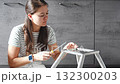 Young woman sitting on the floor assembling a chair with tools. Concept of female independence and do it yourself lifestyle. 132300203