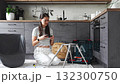 Young woman assembling a chair while watching a video tutorial on her phone at home. Concept of self education, independence, and modern DIY lifestyle 132300750
