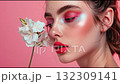 A video of a model with bright pink makeup smelling a white flower. 132309141