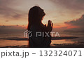 Silhouette of woman with folded hands praying against beautiful sunset near sea concept of humility religion and meditation. Believer woman praying to God 132324071