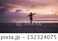 Happy inspired woman rejoices and beautiful tropical sunset on the sea. Female jumps raising her hands and spins in joy and happiness. young woman enjoys evening time on the beach tropical sunset 132324075
