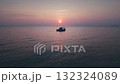 Small ship sailing across tranquil sea, surrounded by stunning pink and purple sky during captivating sunset, creating warm reflections on shimmering water, lonely yacht drifts against sunset sky 132324089