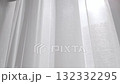 Close-up of white transparent curtain swaying by the wind on a sunny summer day. Modern home interior detail, fresh air coming through the open window. Light fabric moving slowly by the morning breeze 132332295