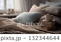 Cozy bedroom scene with pillows and a cup of coffee on stacked books in soft morning light 132344644