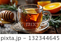 Warm herbal tea with orange slices and honey on a wooden table in a cozy setting 132344645