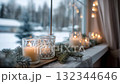 Cozy winter scene featuring candles and decorations on a windowsill with snow-covered landscape outside 132344646