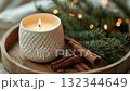 Relaxing ambiance created by a scented candle with cinnamon sticks and pine branches on a cozy surface during winter 132344649