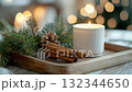Cozy winter arrangement with candle, cinnamon sticks, and greenery on wooden tray 132344650