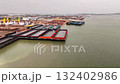 Aerial view of an industrial port with several large barges one featuring a bright orange edge surrounded by cranes and buildings for cargo operations 132402986