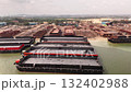 Aerial view of an industrial port with several large barges one featuring a bright orange edge surrounded by cranes and buildings for cargo operations 132402988