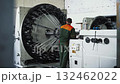Large circular braiding machine operated by technician amid factory 132462022