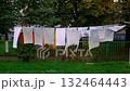 Various clothing items are hanging to dry outside in a sunny backyard area. 132464443