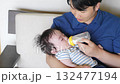 A man feeding a baby with a bottle 132477194