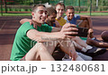 Smiling sporty fit diverse multiracial male basketball players sitting on outdoor court, taking selfie shot on cellphone, expressing cheerful mood and positivity while relaxing after game. Smiling sporty fit diverse multiracial male basketball players sitting on outdoor court, taking selfie shot on cellphone, expressing cheerful mood and positivity while relaxing after game. 132480681