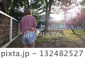 Teenage Girl Watering Lawn and Trees with Garden Hose at Sunset 132482527