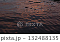 Beautiful pink and orange sunset reflections on dark blue water surface. Continuously changing wavy sea surface for background. Neutral mirror effect, calm and meditative nature concept. 132488135