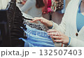 Close-up of woman shopping in fashion store, choosing blue shirt from rack, browsing stylish clothes and enjoying modern retail fashion 132507403