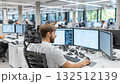 Software engineer working with multiple monitors in busy office 132512139