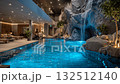 Luxurious indoor swimming pool with waterfall and candles illuminating relaxing spa 132512140