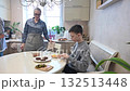 Middle-aged Caucasian woman cooking burgers with her two sons.  132513448