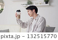 Asian man looking at protein shake in living room 132515770