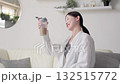 Asian woman looking at protein shake in living room 132515772