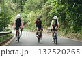 three young asian cyclists riding bicycle on a uphill country road	 132520265