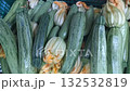 Fresh Green zucchini with yellow flowers sit in a box on a store counter 132532819