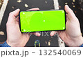 Close-up of a person holding smartphone with green screen outdoors while walking 132540069
