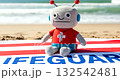 Robot lifeguard toy sitting on a towel at the beach 132542481