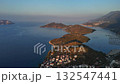 Aerial drone view of Kas Peninsula at sunrise, with calm blue sea, anchored boats, and mountains glowing in the first morning light. Turkey 132547441
