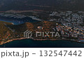 Aerial drone view of Kas marina and ancient amphitheater at sunset, surrounded by hills, yachts, and coastal town architecture along the Mediterranean Sea. Turkey 132547442