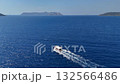 Aerial view of a small boat sailing in the blue sea near Kas, Turkey, with distant islands under a clear sky. 132566486