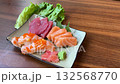 A rectangular plate of assorted sushi, including nigiri, sashimi, and tamago, rotates smoothly against a black background under soft, even lighting 132568770