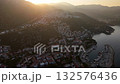 Aerial view of Kas, Turkey, at sunrise showing hillside houses, marina, and calm sea under warm morning light. 132576436