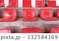 Empty red plastic seats arranged in rows on a concrete stand. The image shows a minimalist composition with bright color contrast and geometric repetition, evoking simplicity 132584169