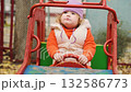 Child enjoys driving a colorful toy car at a playground on a crisp day in autumn with vibrant colors surrounding the scene 132586773