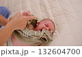 Mother dresses baby girl on bed against the window. Children's room, bedroom. 132604700