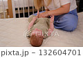 Mother dresses baby girl on bed against the window. Children's room, bedroom. 132604701