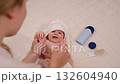 newborn baby in a white bathrobe fun with his mother after bathing and smiling 132604940