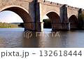 grand bridge scene, massive brick vaults extend across stream, bright sunset illuminates historic industrial landscape and river, sunset bathes old brick arches as river flows peacefully 132618444